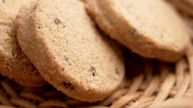 Gourmet taking delicious fresh chocolate chip shortbread cookie from a wicker kitchen bowl with his fingers. Macro shot