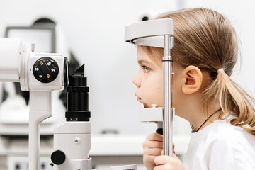 In a modern ophthalmology clinic, an ophthalmologist checks a little girl's vision using a binocular slit lamp in close-up. An example of contemporary techniques for children's vision correction.