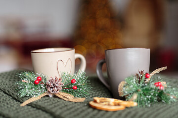 cozy winter composition with a cup of tea, christmas decoration and christmas lights on knitted blanket