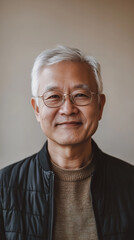 Obraz premium A front portrait of an elderly Asian man, smiling, centered in the frame, short silver hair