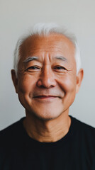 A front portrait of an elderly Asian man, smiling, centered in the frame, short silver hair