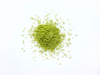 Green herbs powder pebbles scattered randomly and isolated on a white background, view from top.