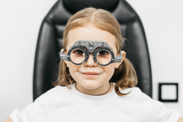 A doctor diagnosing a little girl’s vision and selecting lenses using a modern medical device....
