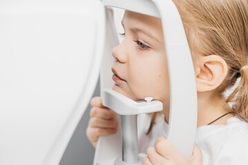 A pediatric optometrist examines the eyes of a little girl. Ophthalmic instrument. An excellent...