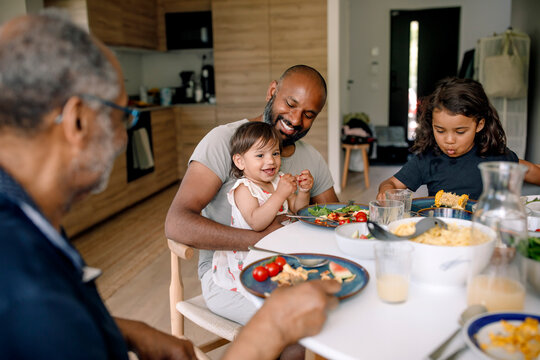Happy multigenerational family having breakfast on dining table at home