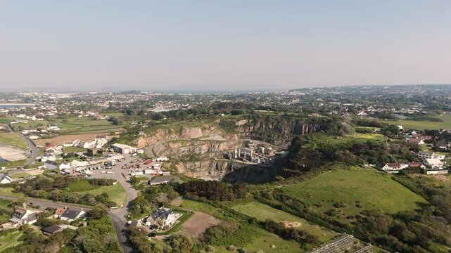 High Rising Drone footage approaching Les Vardes Quarry Guernsey showing quarry, equipment and surrounding area on bright sunny day
