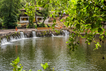 Blurred leaves and weir in stone with small waterfalls flowing water of river Alva at Coja beach, Arganil PORTUGAL