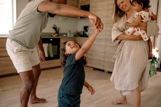 Mature man dancing with son standing in kitchen at home