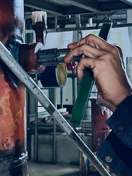 A worker using a threading tool to install a pipe in an industrial setting. The image showcases the process of pipe fitting and precise mechanical work in a construction environment.