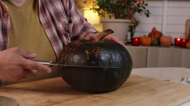 man cuts warm pumpkin in half to make pumpkin pie