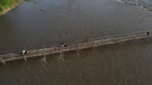 Aerial footage shows a wooden bridge spanning the Progo River, passable by motorbikes. As a link between the villages of Bantul and Kulonprogo.