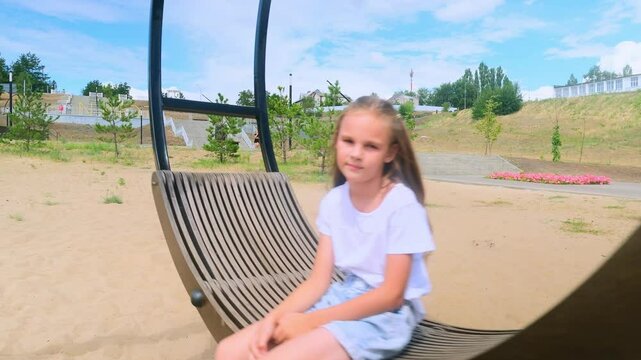 Child plays on wooden swing. Child swing, kid girl smile. Child girl happiness dream entertainment. Happy little girl swings on swing in park. Family walk