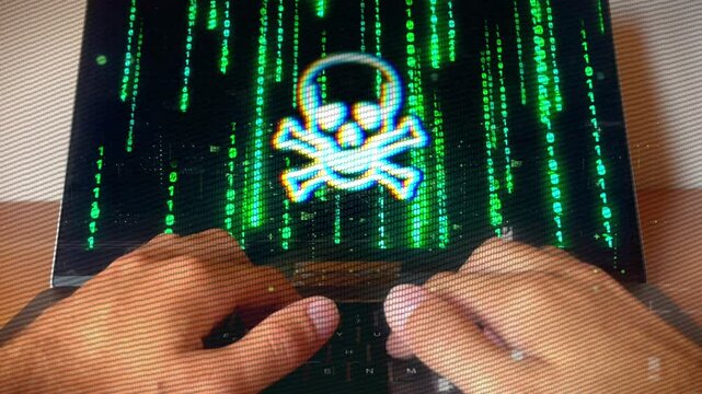 Hacker typing as malware warning symbol displays on screen