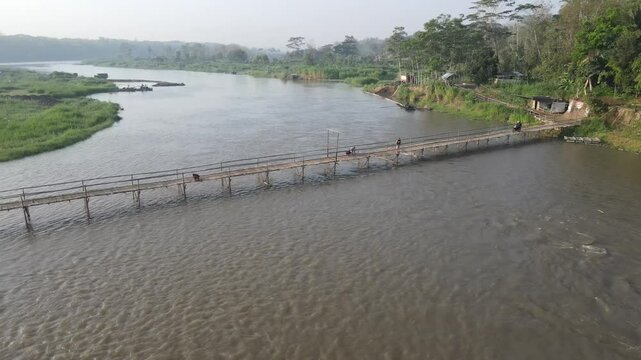 Aerial footage shows a wooden bridge spanning the Progo River, passable by motorbikes. As a link between the villages of Bantul and Kulonprogo.