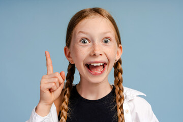 Excited girl raising finger having idea on blue background