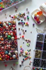 Colorful beads, letter beads, threads and other jewelry making supplies on white background. Making...