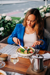 Fit adult beautiful woman dressed business style jacket in cafeteria street eating her launch salad with shrimp and avocado. Healthy food with seafood and vegetables