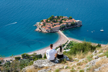 Couple enjoying breathtaking views of Sveti Stefan in Montenegro on a sunny day