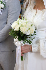 The bride is holding a beautiful bouquet of white roses.