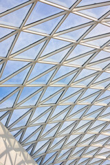 Fototapeta premium Glass roof of the mall inside view with part of white concrete wall and lightning protection system outside. Vertical shot.