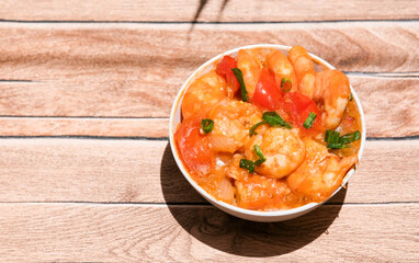 Udang asam manis or sweet and sour shrimp. one of chinese cuisine, shrimp is cooked with garlick, leek, chilli and a sweet and sour sauce added to the white bowl before serving.