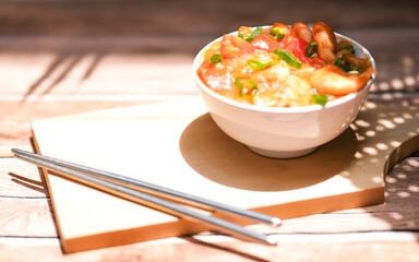 Udang asam manis or sweet and sour shrimp. one of chinese cuisine, shrimp is cooked with garlick, leek, chilli and a sweet and sour sauce added to the white bowl before serving.