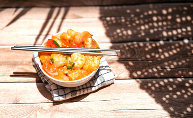 Udang asam manis or sweet and sour shrimp. one of chinese cuisine, shrimp is cooked with garlick, leek, chilli and a sweet and sour sauce added to the white bowl before serving.