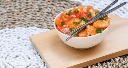 Udang asam manis or sweet and sour shrimp. one of chinese cuisine, shrimp is cooked with garlick, leek, chilli and a sweet and sour sauce added to the white bowl before serving.