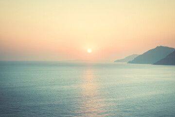 Beautiful sunset over calm waters with distant mountains along the coastline