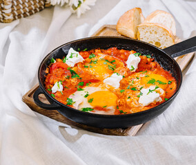 Spicy shakshuka with eggs and feta cheese garnished with parsley in a cast iron skillet