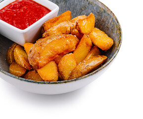 Bowl of potato wedges with tomato sauce and a rustic background