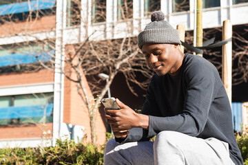 Happy black man checks cell phone on street