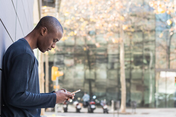 Worried man with black skin checking mobile phone in a park