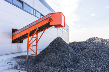 Tire recycling facility with shredded rubber piles and conveyor belt