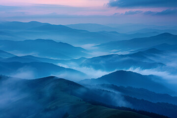 Misty mountain range at dawn with soft blue hues and rolling fog creating a serene landscape