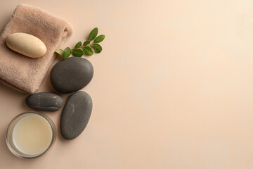 massage stones, oils and towels on a beige background, space for text