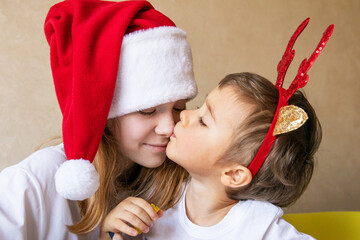 Little boy kissing his older sister on nose wearing New Year hats eve Happy New Year Merry Christmas