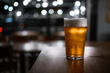 Rustic pub table with a pint of ale and bokeh light circles in the background