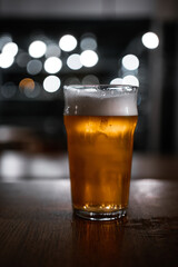 Rustic pub table with a pint of ale and bokeh light circles in the background
