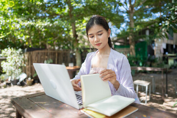 Beautiful confident freelancer asian young woman working with laptop Hands typing keyboard. digital nomad working remotely from outdoor eco cafe Workplace on nature outdoors