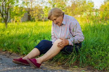 Old woman has knee pain in nature. Selective focus.