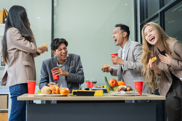 Asian business team are excited business success with inspiration from their excellent financial results, celebration successful deal with champagne and pizza in the workplace.