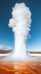 A large geyser spews out steam and water into the air. The sky is clear and blue, and the geyser is surrounded by a snowy landscape