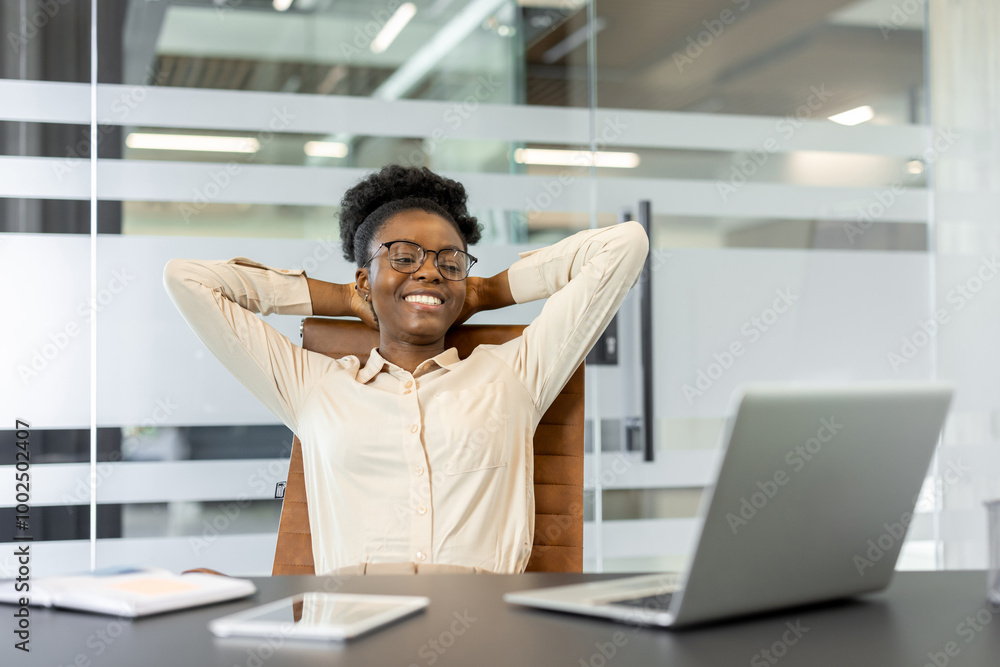 Wall mural businesswoman enjoying break at office desk. smiling woman leans back in chair, feeling relaxed and 