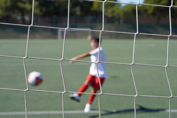 goal net with player kicking the ball in the background
