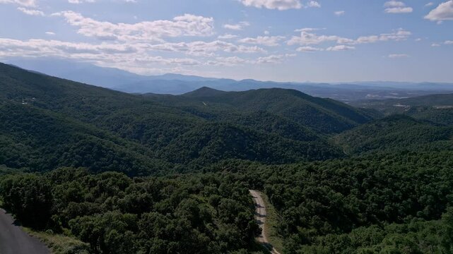 Road passing through mountain forest near Le Perthus, France. Aerial dolly right