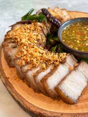 Deliciously prepared sliced pork served on a wooden platter with flavorful dipping sauce and...