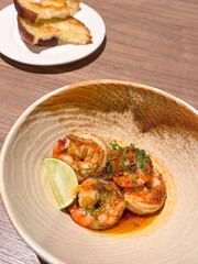 Delicious grilled shrimp served with lime and herbs on a stylish plate, ideal for food lovers and culinary presentations.