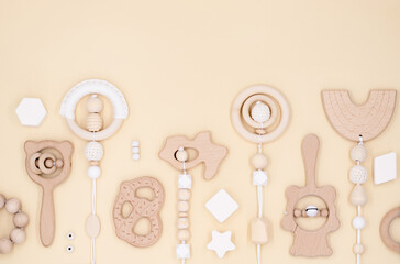 Pattern kids accessories, newborn baby things, children's toys made of natural wood on pastel beige background, top view, flat lay with copy space
