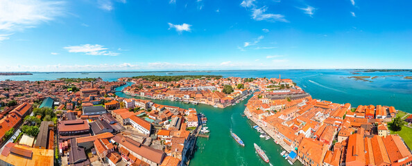 Aerial panoramic view of the Murano island in Venetian lagoon. Rooftops, canals and boats